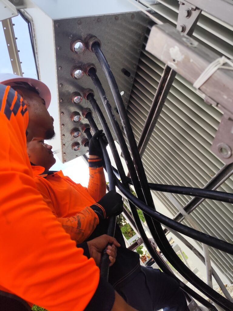 Local electrical fitters installing large cables into a BESS transformer